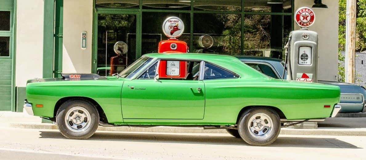 Green classic car stops for gas